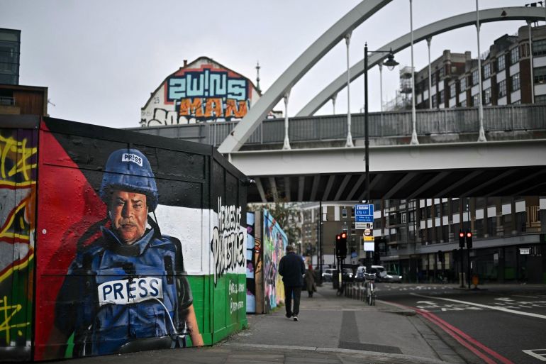 A pedestrian walks past a graffiti made by Spanish street artist Nacho Welles, also known as Core246, depicting Palestinian journalist and bureau chief of Al Jazeera in Gaza City Wael al-Dahdouh, as part of a project launched by the art platform Creative Debuts called "Heroes of Palestine", in east London, on January 29, 2024. Al Jazeera's Gaza bureau chief Wael al-Dahdouh left the Palestinian territory on January 16, 2024, he told AFP, after Israeli strikes killed his wife, multiple children and a colleague. At least 24,285 Palestinians have been killed in the Gaza Strip in Israeli bombardments and ground offensive since October 7, according to the Hamas government's health ministry. The unprecedented Hamas attack on October 7 resulted in the death of around 1,140 people in Israel, according to an AFP tally based on official Israeli figures. (Photo by Ben Stansall / AFP) / RESTRICTED TO EDITORIAL USE - MANDATORY MENTION OF THE ARTIST UPON PUBLICATION - TO ILLUSTRATE THE EVENT AS SPECIFIED IN THE CAPTION - RESTRICTED TO EDITORIAL USE - MANDATORY MENTION OF THE ARTIST UPON PUBLICATION - TO ILLUSTRATE THE EVENT AS SPECIFIED IN THE CAPTION