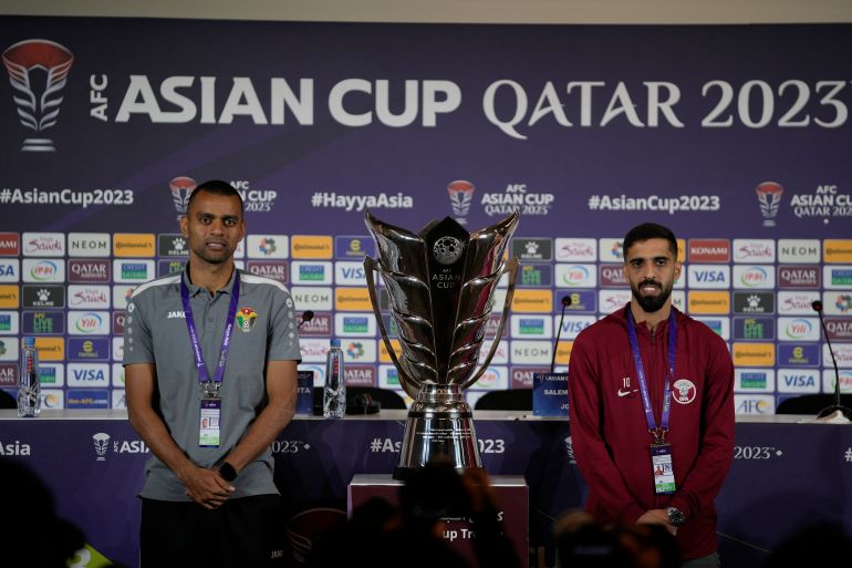 Jordan's Salem Al Ajalin, left, and Qatar's Hasan Al Haydos pose next to the Asian Cup trophy ahead of a press conference in Doha, Qatar, Friday, Feb. 9, 2024. Jordan will play Qatar on Saturday for the soccer final of the Asian Cup. (AP Photo/Thanassis Stavrakis)
