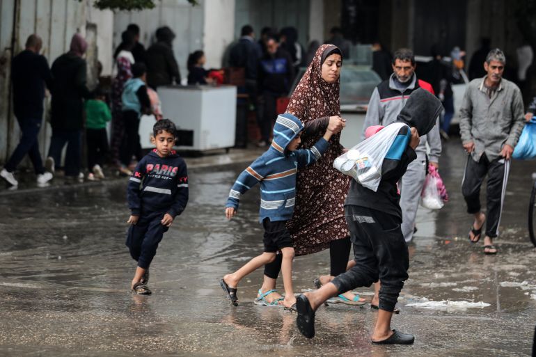 Palestinians are walking along a flooded street following heavy rains in Deir El-Balah, in the central Gaza Strip, on December 12, 2023, amid ongoing battles between Israel and the Palestinian militant group Hamas. (Photo by Majdi Fathi/NurPhoto via Getty Images)