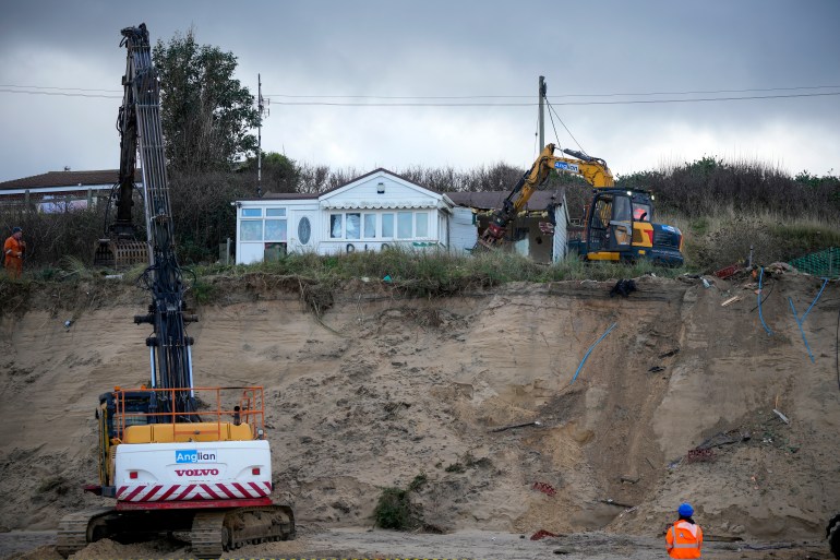HEMSBY, ENGLAND - DECEMBER 11: A beach chalet is demolished by workers before it falls down the sea cliff on The Marrams at Hemsby Beach on December 11, 2023 in Hemsby, England. The collapse of a private access road in November, prompted by high tides and winds, led Great Yarmouth Borough Council to declare the rapidly eroding homes on The Marrams 'not structurally sound and unsafe.' This demolition coincides with the 10th anniversary of five village houses lost to the sea in 2013 when storms undermined foundations by stripping away significant sand. (Photo by Christopher Furlong/Getty Images)