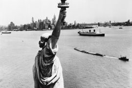 (Original Caption) 6/11/57-New York: A striking view of New York Harbor and the magnificent skyline of lower Manhattan, made from behind the Statue of Liberty, who stands with torch aloft waiting to welcome the arrival and speed the departing guest. At the moment the French liner Ile de France is outward bound past the statue. While in foreground a grunting tug hauls a string of barges. To the right of the tip of Manhattan Island is the East River and its bridges. BPA2 #4794