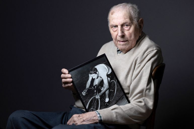 Olympic champion in Men's Team Pursuit in track cycling at the 1948 London Games, Charles Coste, poses with a photo of himself when he was competing during a photo session at home in Bois-Colombes, northwestern of Paris, on January 30, 2024. Charles Coste is the oldest living French Olympic champion. (Photo by JOEL SAGET / AFP)Olympic champion in Men's Team Pursuit in track cycling at the 1948 London Games, Charles Coste, poses with a photo of himself when he was competing during a photo session at home in Bois-Colombes, northwestern of Paris, on January 30, 2024. Charles Coste is the oldest living French Olympic champion. (Photo by JOEL SAGET / AFP)
