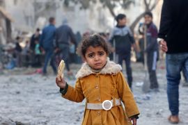 EDITORS NOTE: Graphic content / A Palestinian girl eats a piece of bread as people check debris on February 22, 2024, following overnight Israeli air strikes in Rafah refugee camp in the southern Gaza Strip, as battles between Israel and the Palestinian militant group Hamas continue. (Photo by MOHAMMED ABED / AFP)