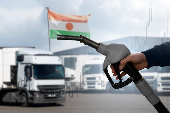 A hand with a fuel nozzle on the background of trucks. The concept of a fuel crisis due to rising prices.