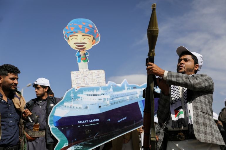A Houthi follower holds a rocket launcher as others carry a cutout banner, portraying the Galaxy Leader cargo ship which was seized by Houthis, during a parade as part of a 'popular army' mobilization campaign by the movement, in Sanaa, Yemen, February 7, 2024. REUTERS/Khaled Abdullah