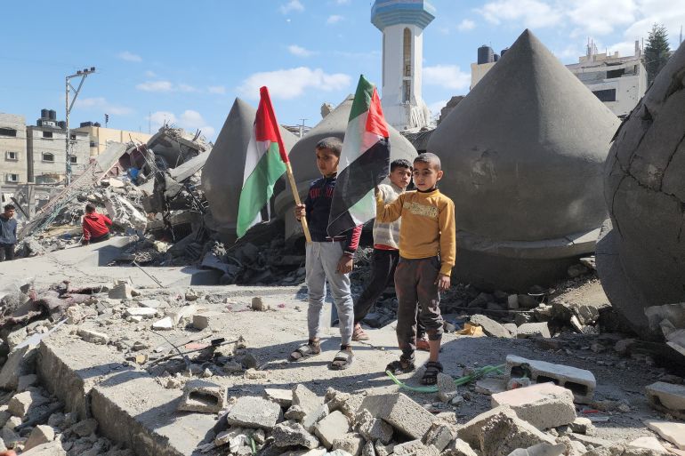 أطفال يلوحون بالعلم الفلسطيني فوق أنقاض مسجد الفاروق المدمر بمخيم الشابورة بمدينة رفح-رائد موسى-رفح-الجزيرة نت