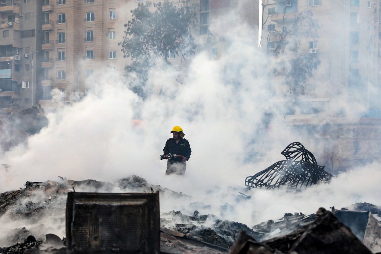 A firefighter cools the area still smouldering after a fire at the Al-Ahram Studio and surrounding buildings in Cairo's Giza district on March 16, 2024. - Flames overtook one of the Arab world's most prestigious and oldest film production studios founded 80 years ago, burning everything inside and spreading to three surrounding buildings which were evacuated before the blaze reached them. (Photo by Momen SAMIR / AFP)