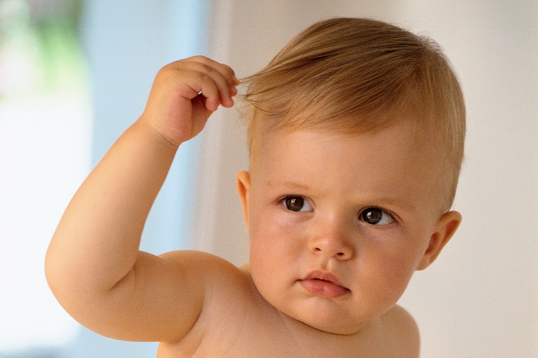 Baby pulling on hair - stock photo