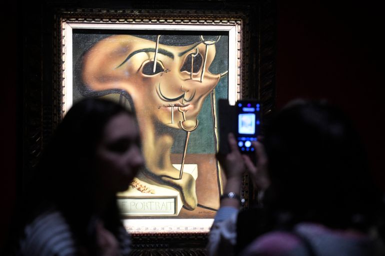 Visitors take pictures of the painting 'Soft Self-Portrait with Fried Bacon' (oil on canvas, 1941) by Spanish artist and surrealist icon Salvador Dali (1904 - 1989) during the exhibition "Salvador Dali - Magic Art" hosted at the Manege Central Exhibition Hall in Moscow on January 30, 2020. The exhibition features over 180 works by Dali and will be open to the public until March 25, 2020. (Photo by Alexander NEMENOV / AFP) / RESTRICTED TO EDITORIAL USE - MANDATORY MENTION OF THE ARTIST UPON PUBLICATION - TO ILLUSTRATE THE EVENT AS SPECIFIED IN THE CAPTION
