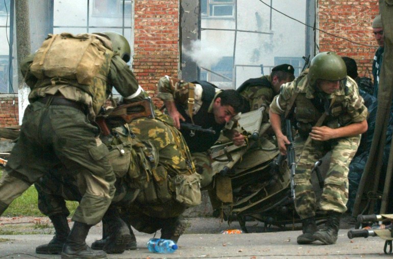 Russian special forces troops run for cover while soldiers stormed a building seized by heavily armed masked men and women in the town of Beslan in the province of North Ossetia near Chechnya, September 3, 2004. Russian soldiers battled Chechen separatists on Friday to end a two-day-old school siege as naked children ran out screaming amid explosions and machinegun fire. REUTERS/Sergei Karpukhin GD/DBP