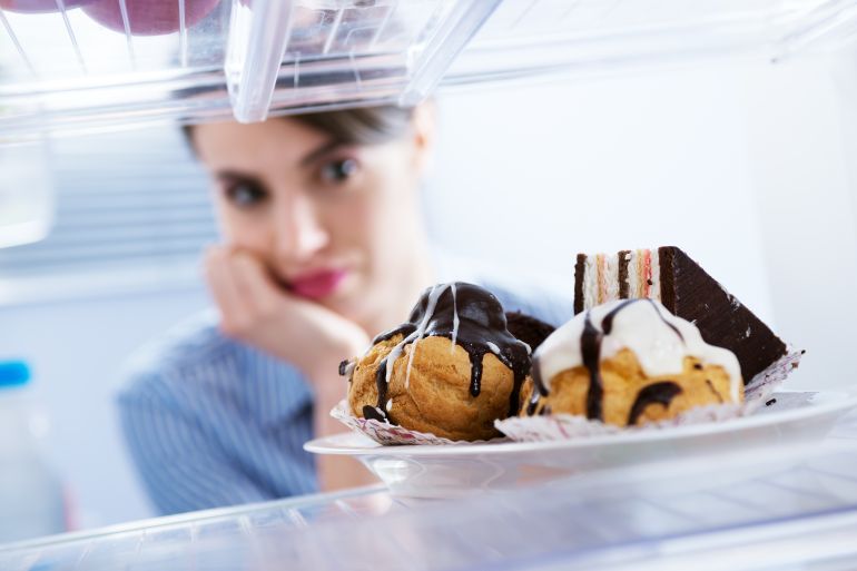 Young hungry woman in front of refrigerator craving chocolate pastries.; Shutterstock ID 176923985; purchase_order: ajnet; job: ; client: ; other: