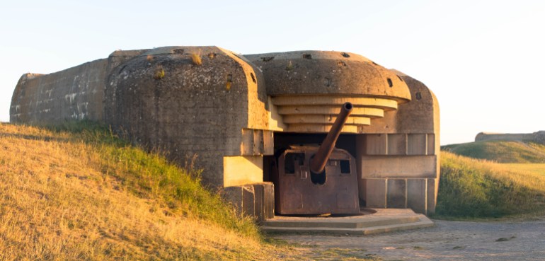 Gun emplacement at Omaha Beach. Bomb shelter with german long-range artillery gun from world war 2 in Longues-sur-Mer in Normandy. France