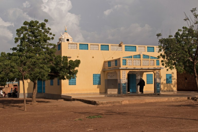 Kongoussi, Burkina Faso - Oct 19, 2019: Muslim man entering the Great Mosque of Kongoussi (Grande Mosquée De Kongoussi) for prayer. Islam is the most popular religion in Burkina Faso.