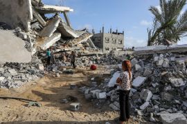 طفلة في رفح تراقب منزل عائلة عبد العال الذي دمره قصف إسرائيلي (الأناضول)