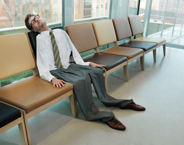 Businessman on a row of chairs with a deflated body. sleeping
