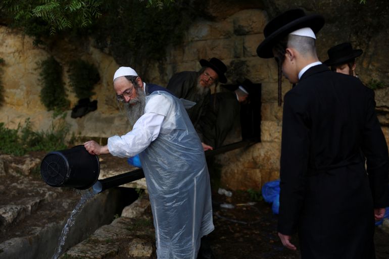 Ultra-Orthodox Jews take part in the "Mayim Shelanu" ceremony in which water is collected from a natural spring for the preparation of matza, the traditional unleavened bread eaten during the upcoming Jewish holiday of Passover, near Jerusalem in the Israeli-occupied West Bank, April 21, 2024. REUTERS/Hannah Mckay