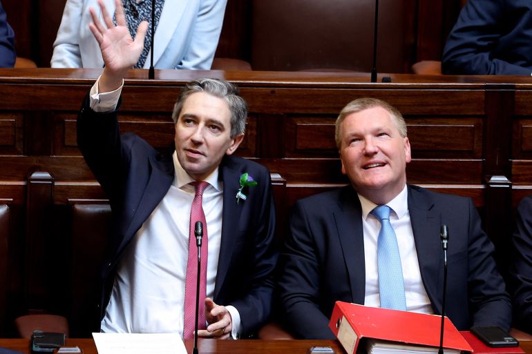 A handout photograph taken on, and released by Ireland's Houses of the Oireachtas on April 9, 2024 shows Fine Gael leader and Ireland's incoming Prime Minster, Simon Harris (L) waving in the Dail, the lower house of the Irish parliament, in Dublin, before being voted in as Ireland's new Prime Minister. Simon Harris on Tuesday became Ireland's new prime minister, replacing Leo Varadkar after he abruptly quit last month citing personal and political reasons. Ireland's parliament voted 88 to 69 in favour of Harris, 37, becoming "taoiseach" -- a Gaelic word for "chieftain" or "leader" pronounced "tee-shock". - RESTRICTED TO EDITORIAL USE - MANDATORY CREDIT "AFP PHOTO / HOUSES OF THE OIREACHTAS / MAXWELLS " - NO MARKETING - NO ADVERTISING CAMPAIGNS - DISTRIBUTED AS A SERVICE TO CLIENTS (Photo by MAXWELLS / HOUSES OF THE OIREACHTAS / AFP) / RESTRICTED TO EDITORIAL USE - MANDATORY CREDIT "AFP PHOTO / HOUSES OF THE OIREACHTAS / MAXWELLS " - NO MARKETING - NO ADVERTISING CAMPAIGNS - DISTRIBUTED AS A SERVICE TO CLIENTS