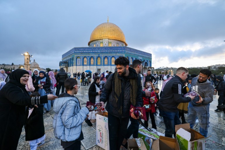 Volunteers distribute dates as Muslims arrive to offer special morning prayers to start the Eid al-Fitr festival, which marks the end of the holy fasting month of Ramadan, at the Al-Aqsa Mosque compound in Jerusalem on April 10, 2024. (Photo by AHMAD GHARABLI / AFP)
