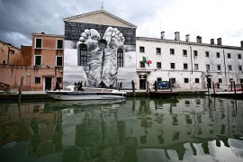 لوحة جدارية للفنان ماوريتسيو كاتيلان خلال افتتاح بينالي البندقية في المدينة الإيطالية (الفرنسية)