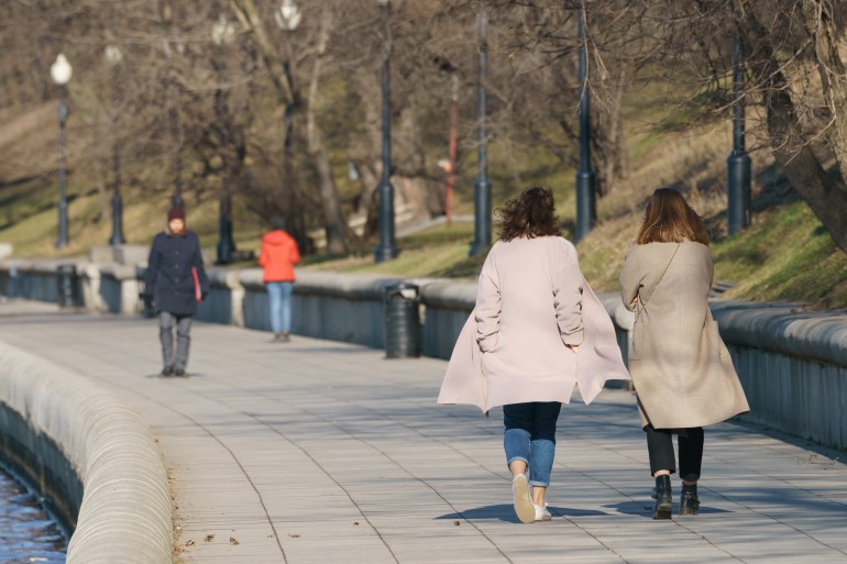People walking in the Sparrow Hills (Vorobyovy Gory) public park in the spring day. Few people. Two friends. Lifestyle of big city. Backs, rear view; Shutterstock ID 2135484691; purchase_order: aljazeera ; job: ; client: ; other: