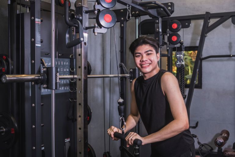 A young asian man does a set of straight bar tricep pushdowns. A first time beginner tries to building muscle mass on his arms and upper torso. Modern gym setting المصدر: أدوبي ستوك
