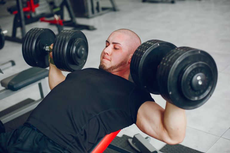 A young and muscular guy in a black t-shirt trains in a gym المصدر: Magnific AI