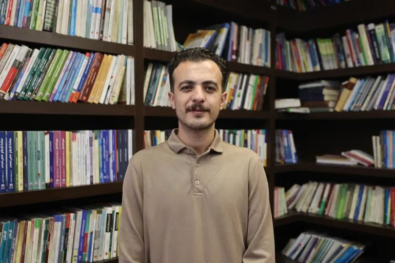 يقف عمر حمد، مؤسس "مكتبة الفينيق"، وسط كتب أُنقذت من مكتبات ومنازل في أنحاء قطاع غزة، محافظاً بذلك على مجموعة نجت من الدمار