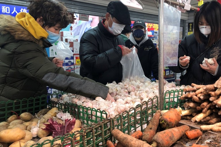 People wearing face masks select vegetables at a supermarket, as the country is hit by an outbreak of the new coronavirus, in Beijing, China January 26, 2020. REUTERS/Carlos Garcia Rawlins