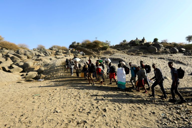 Ethiopians who fled the ongoing fighting in Tigray region, carry their belongings from a boat after crossing the Setit river on the Sudan-Ethiopia border in Hamdayet village in eastern Kassala state