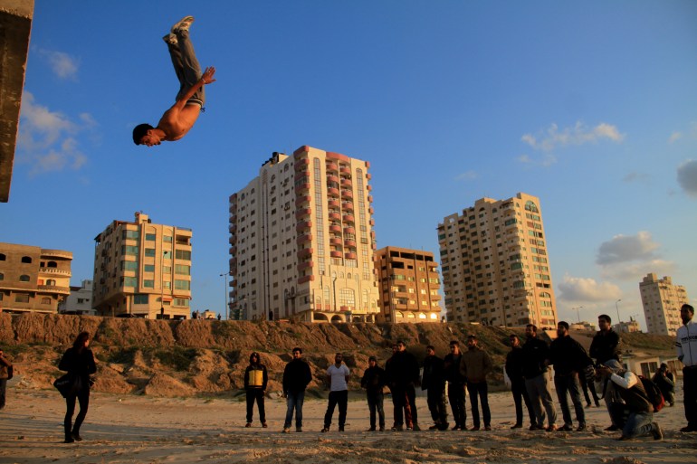 شاب يؤدي حركات أكروباتية في ساحة عامة في غزة-رائد موسى-الجزيرة نت