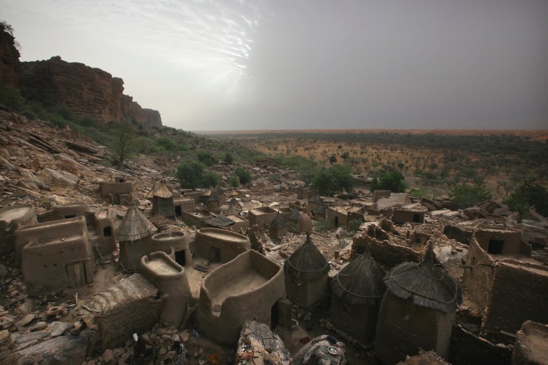 Traditional mud huts and thatched granaries in a Dogon village by the Bandiagara cliffs. Location: Bandiagara Escarpment ( The cliffs of Bandiagara ), Dogon Country, Mopti Region, The Sahel, Mali.