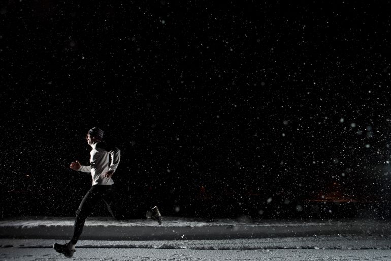Man running at night in snowstorm. - stock photo