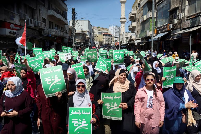 Demonstrators carry flags and banners during a protest in support of Palestinians in Gaza, amid the ongoing conflict between Israel and the Palestinian Islamist group Hamas, in Amman, Jordan April 12, 2024. The green banners read: ' Our Eid is with the victory of Gaza'. REUTERS/Jehad Shelbak